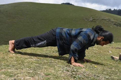 Full length side view of a handsome long haired Indian young man doing push ups  Stock Photos