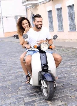 Full length side view of happy couple riding on retro motorbike Stock Photos