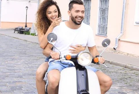 Full length side view of happy couple riding on retro motorbike Stock Photos