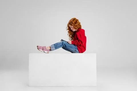 Full-length side view portrait of little curly smiling girl, child sitting with Stock Photos