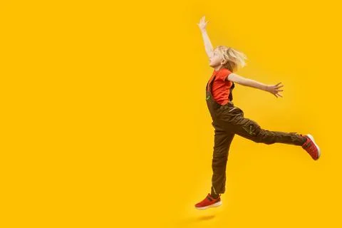 Full-length Side view portrait of bouncing boy on yellow background. Child .. Stock-Fotos