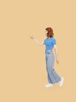 Full length side view young 20s caucasian woman walking and pointing aside Stock Photos