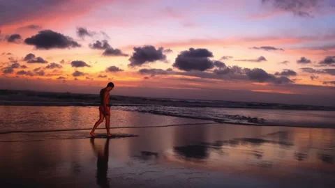 Full-length silhouette of man walking along ocean against backdrop of bright 動画素材 220440124