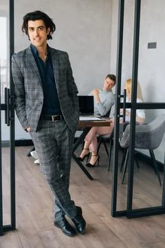 Full length vertical portrait of friendly businessman in suit standing in modern Stock Photos