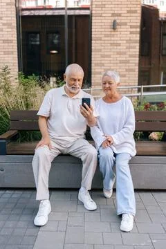 Full length vertical portrait of gray-haired elderly man and woman having online Stock Photos