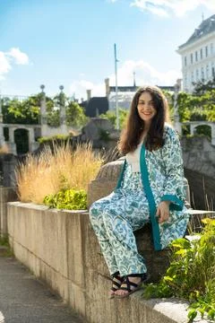 Full length vertical portrait of smiling 38 year old Armenian woman sitting.. Stock Photos