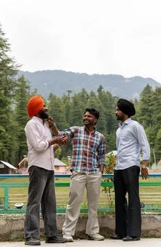 Full-length vertical shot of three Indian friends including two Sikh men. 库存照片