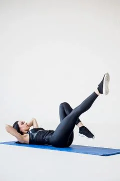 Full-length view of the athletic trainer warming up at the white background. The Stock Photos