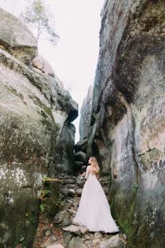 The full-length view of the bride standing on the huge rocks. Fotos de archivo
