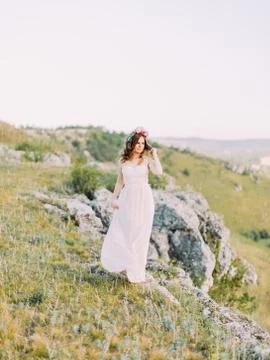 The full-length view of the bride touching her hair and looking aside at the Stock Photos