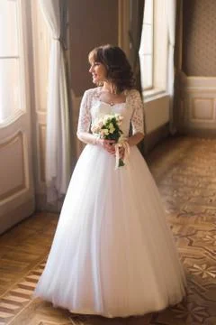 Full-length view of the bride with the wedding bouquet looking through the Stock Photos