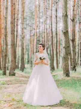 Full-length view of the charming bride with the wedding bouquet looking aside in Stock Photos