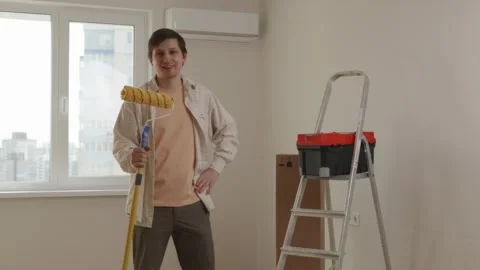 Full length view of man with paint roller and toolbox in house Stock Footage 346159383