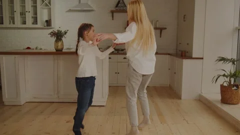Full length view of mother and daughter holding hands while dancing at home Stock Footage 242610384