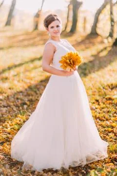 The full-length view of the smiling bride holding the bouquet of the yellowed Stock Photos