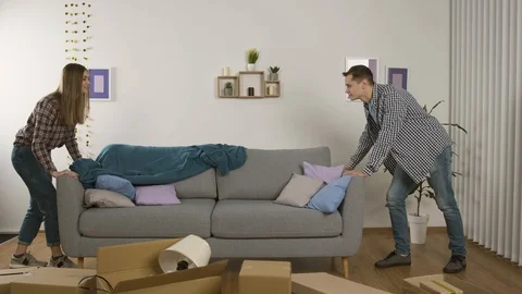 Full length view of smiling couple moving couch and showing thumbs up Vídeo Stock 125322684