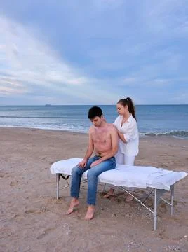 Full length view of a young man with bare torso sitting on a massage table Stock Photos