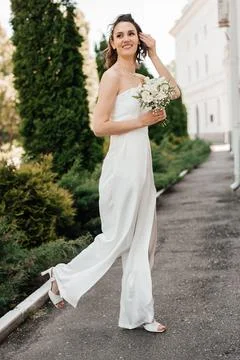 Full length walking bride in white dress holding bouquet of flowers Stock Photos