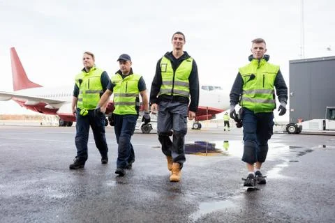 Full Length Of Workers Walking On Wet Runway Stock Photos