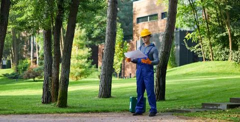 Full length of young builder standing outdoors with blueprint while working on Stock Photos