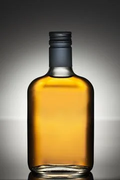 Full liquor bottle on a grey gradient background. side view. Stock Photos