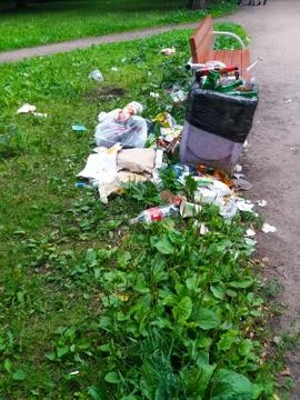 Full litter bin in the park next to the bench Stock Photos