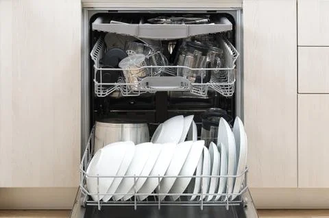 Full loaded Dishwasher machine. Integrated Dishwasher with white plates front Stock Photos