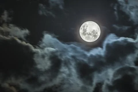 Full moon in between the clouds and idyllic scenery. Amazing the moon rough s Stock Photos