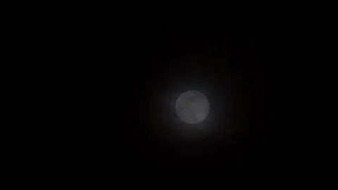 Full moon centered-right in wide dark night sky with soft clouds Video stock 341664366