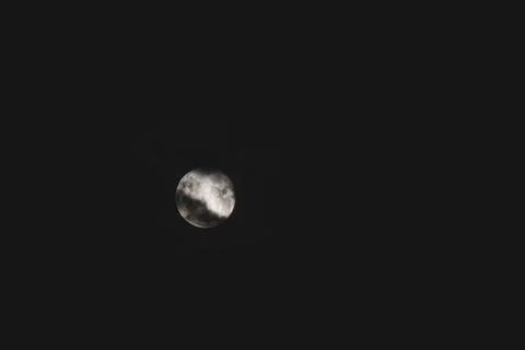 Full moon with dark clouds in front of it in the night sky Stock Photos