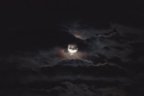 Full moon with dark clouds in front of it in the night sky Stock Photos
