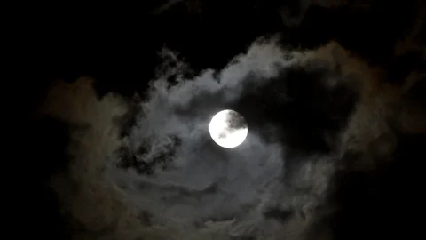 Full moon on a dark night with clouds moving over it Stock Footage