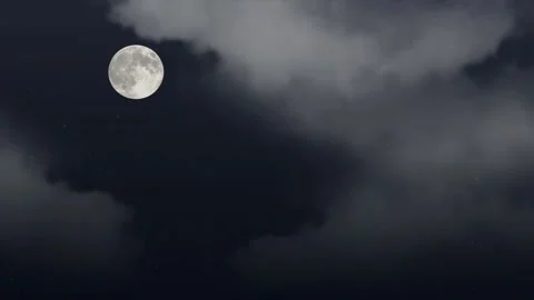 Full moon glowing brightly amidst dark drifting clouds across night sky cosmic Stock Footage 340940527