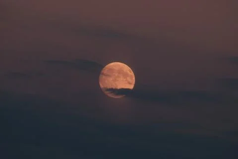 Full moon glowing through dramatic dark evening clouds at twilight. Versatile Stock Photos