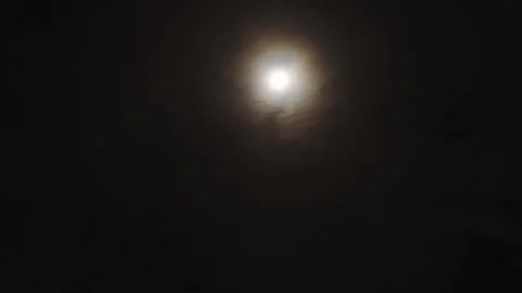 Full moon with halo at night, surrounded by thin clouds in a dark sky Stock Footage 328214462