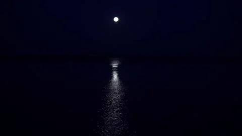 The full moon hangs very low above the horizon in a very calm sea two hours Stock Footage 132499024