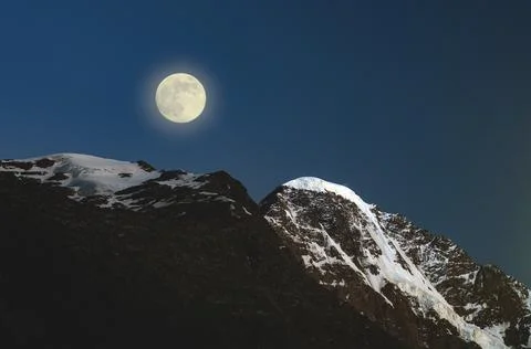 Full moon in the mountains. The moon illuminates the snowy peaks of the mount Stock Photos