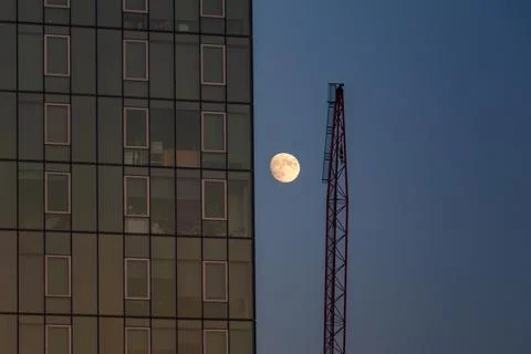A full moon next to a Manhattan skyscraper building and a crane Stock Photos