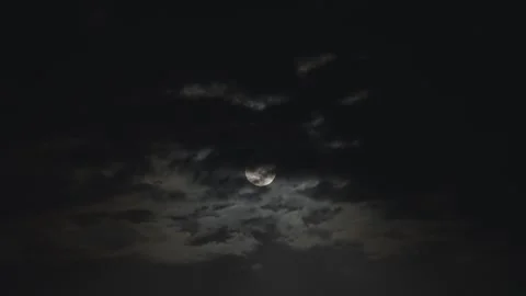 Full moon in the night sky covered almost completely by dark clouds Stock Footage 284455507