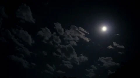 A full moon in the night sky illuminates slowly floating clouds. Stock Footage 134119320
