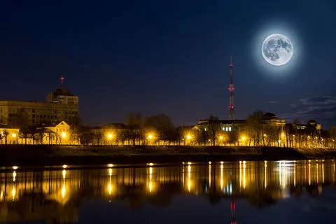 Full moon over the city. Night landscape. Lantern lights are reflected in w.. Fotos Stock
