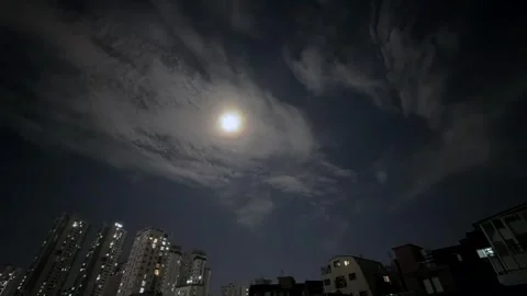 Full moon over city skyline with fast moving clouds in night sky, dramatic Stock Footage 337104789