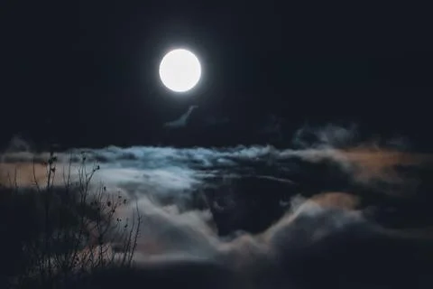 Full moon over clouds and fog in night sky, nebulous blurry landscape Stock-Fotos