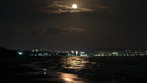 Full moon over the night sea moonlight path on background of seaside town Stock Footage 224449612