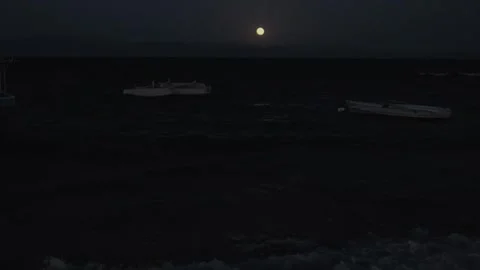 Full moon over rough ocean waves at night with boats and moonlight reflection Vidéo 346708109