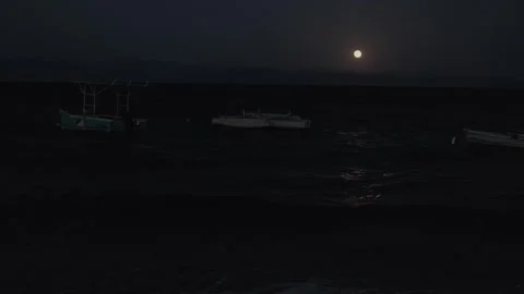 Full moon over rough ocean waves at night, boats rocking on the water and Stockbeeldmateriaal 347305663