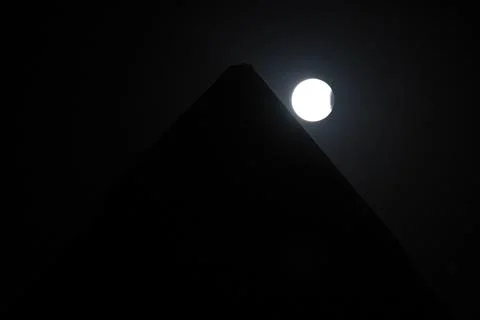 Full moon with a partial lunar eclipse behind Giza pyramids, Egypt - 18 Sep 2024 Stock Photos
