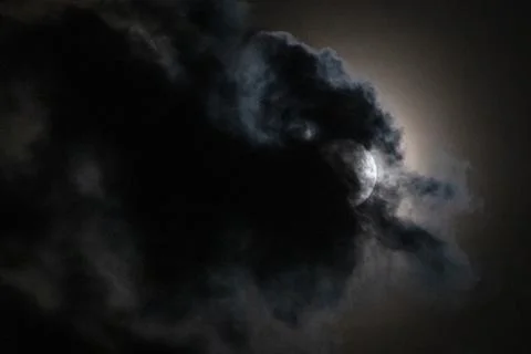 Full moon partially hidden by dramatic dark clouds at night Stock Photos