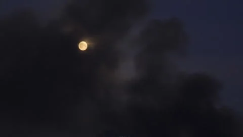 Full moon partially obscured by thick black smoke from a fire caused  Vidéo 336188481