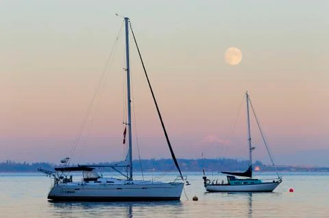 A full moon rises above two sailboats with Mt. Baker in the distance, Mill Bay, Stock Photos